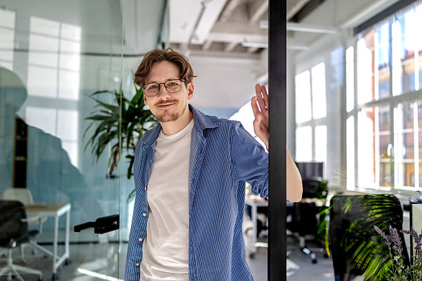 istock Young man engaged in freelance work at a modern office space, showcasing a confident and positive demeanor 2238915400