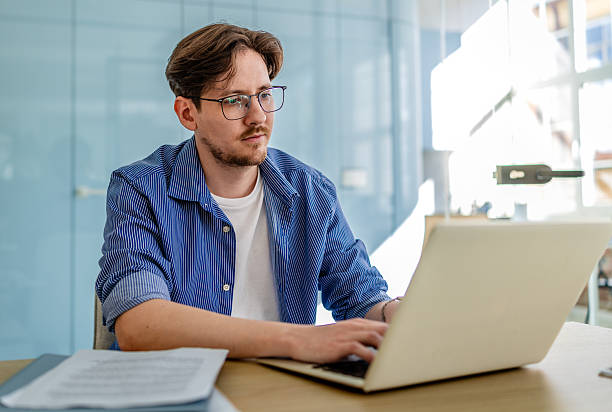 istock Young man engaged in freelance work at a modern office space, showcasing professionalism and positivity 2238915437