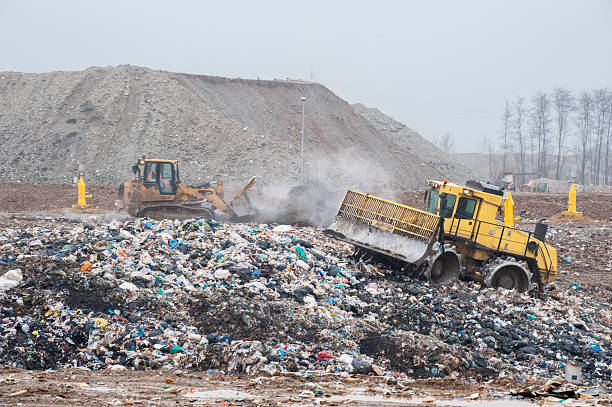 Municipal waste landfill. Workers with trucks and bulldozers at work in the waste storage landfill.