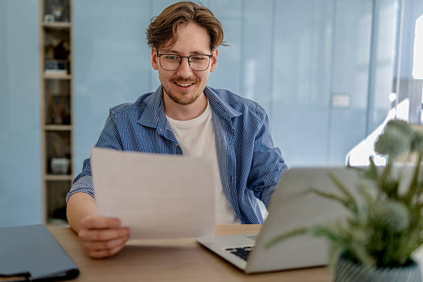 istock Young man happily working at his desk in a modern office environment while engaging with his computer and documents 2238918500