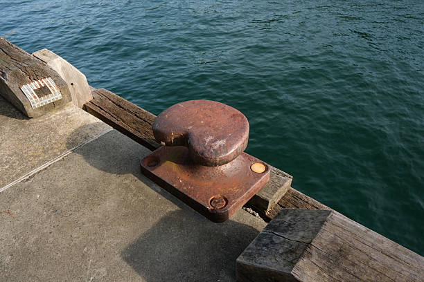Old rusty mooring bollard on a pier on a sunny day.
