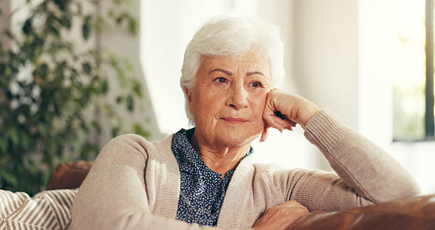 istock Thinking, reflection and senior woman on sofa in home for relaxing, memory or nostalgia in living room. Ideas, retirement and elderly female person with choice, planning or decision in house. 2238921117