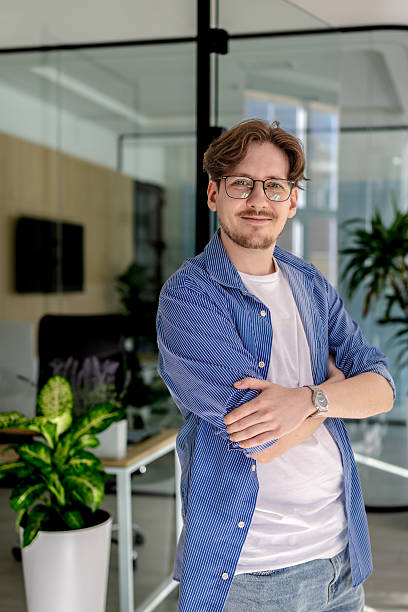 istock Young man smiling confidently while working in a modern office environment with greenery and technology 2238922215