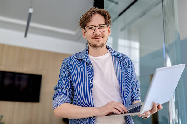istock Young white man enjoys freelance work in a modern office space while smiling confidently 2238926021
