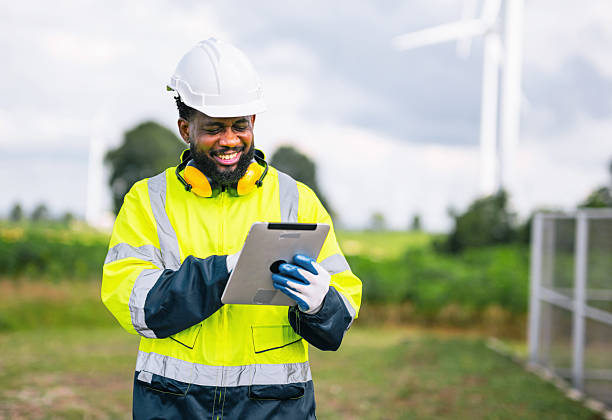 istock man in yellow and black safety suit is smiling while looking at  tablet 2238929955