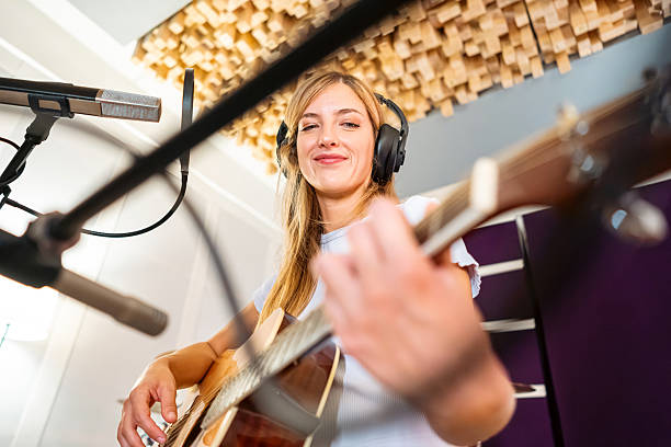 Female musician in a warm recording studio playing guitar during a soundcheck session
