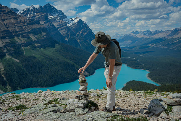 istock Hiker stacking stones with scenic mountain lake backdrop 2238934521
