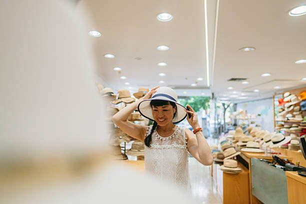 Photo of a beautiful Japanese woman trying on sun straw hat at the Hat store