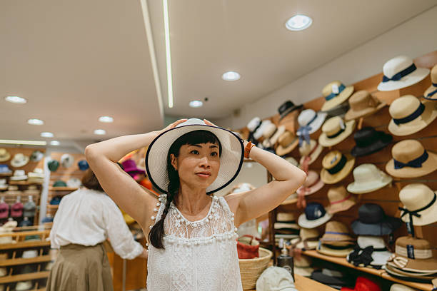 Photo of a beautiful Japanese woman trying on sun straw hat at the Hat store