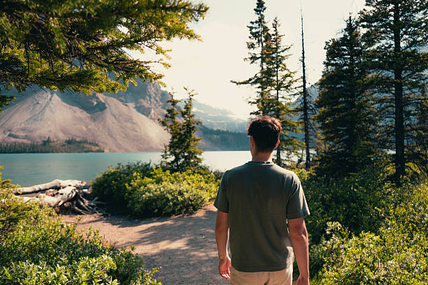 Man contemplates the mountain lake view, surrounded by lush greenery.