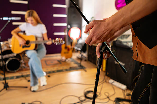 istock Female guitarist in a recording studio during soundcheck with engineer adjusting the microphone 2238936139