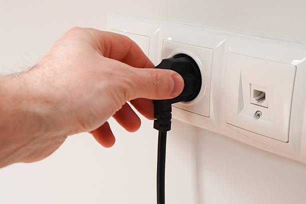 istock Man putting on or removing electric plug cable in socket, closeup. Electrical equipment wires and power strips on the wall 2238941312