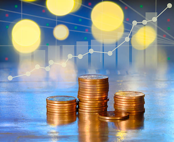 istock coin stacks on a reflective surface against a glowing blue digital stock market graph. Business finance, wealth mangement,investment, and economic growth concept with abstract bokeh background. Free copy space. 2238942760
