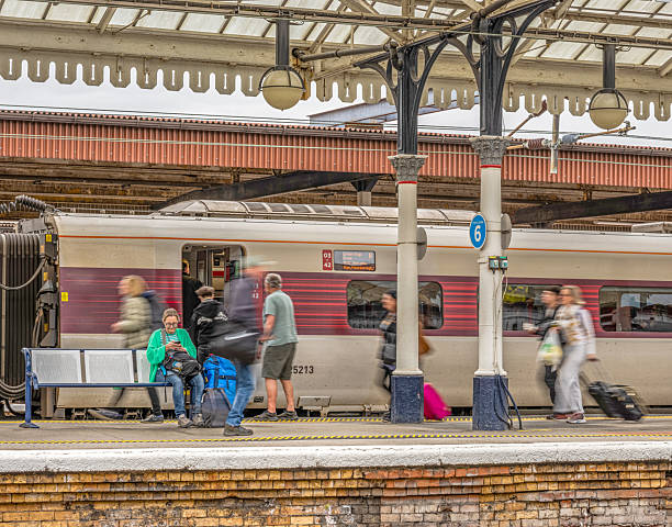 York, UK.  September 26, 2025.  Passengers on a railway station platform rush to board a train while a woman is static sitting on a bench. A carriage is in the background