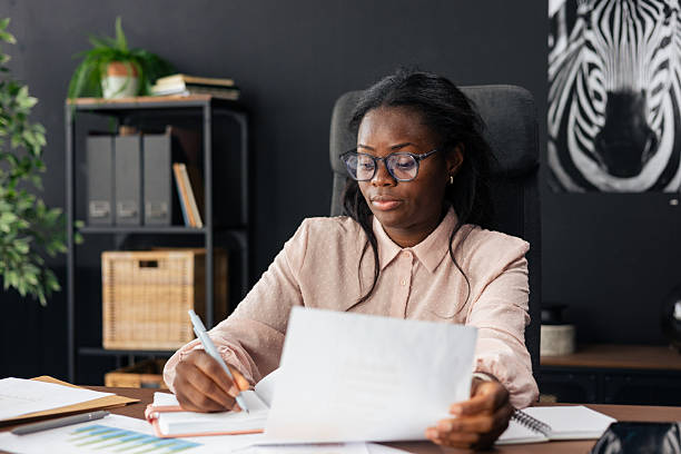 istock Black businesswoman writing notes and reviewing documents at office desk 2238947139