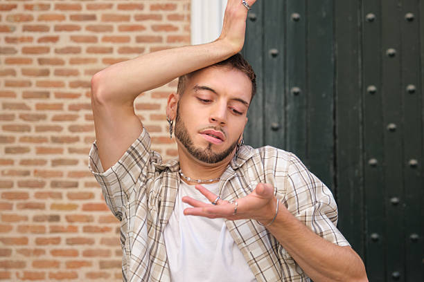 Young gen Z man striking a pose against a textured brick wall with a wooden door