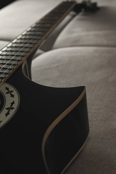 istock Strumming a beautiful black guitar on a cozy couch in soft evening light 2238952776