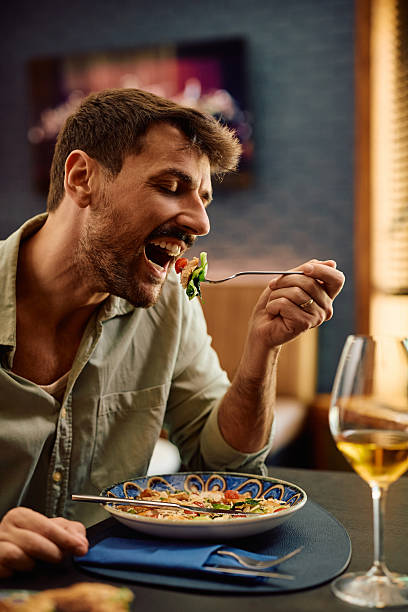 Smiling man enjoying in taste of salad while eating in restaurant.