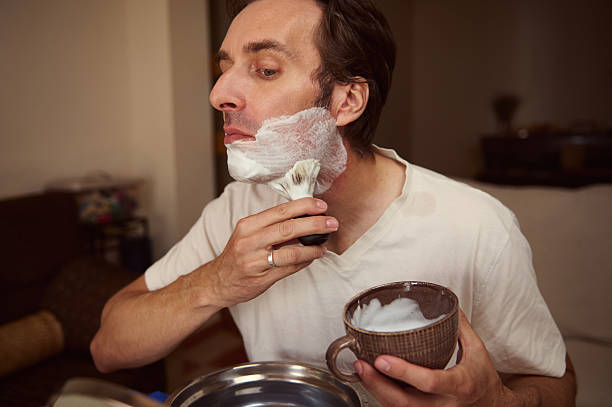 istock Man Shaving at Home With Brush, Foam, and Cup During Morning Routine 2238959676