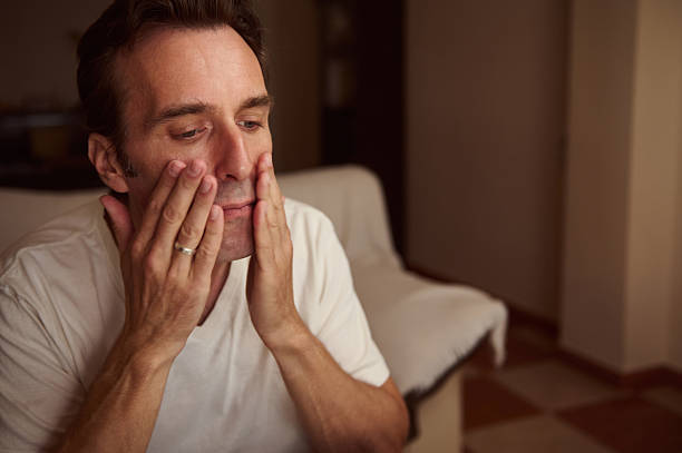 istock Man In White T-Shirt Touching His Face At Home In Soft Evening Light 2238959791