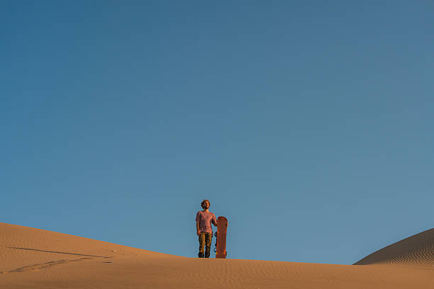 Sporty tourist woman making hand stand on the top of big sand dune, in front of  spectacular Licancabur volcano view in Death Valley, close to San Pedro de Atacama in Chile. Tourist attraction with view on Andes