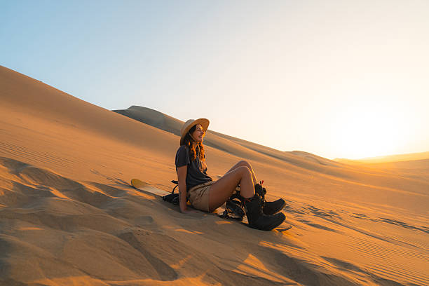 Woman sandboarding in desert in Peru at sunset