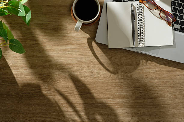 istock Cozy workspace with laptop, notebook, glasses, and coffee cup on a wooden desk. 2238964907