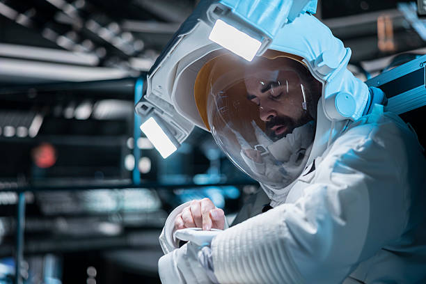 Astronaut pressing wrist touchscreen display to send SOS message to ground control on Earth, alerted by emergency warning. Man in defective spaceship activates onboard backup systems