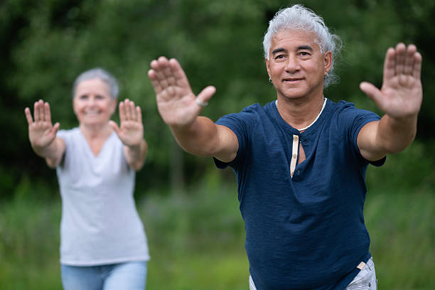 istock Older Couple Outdoors Practice Balance Exercise in Park, Hands Extended Toward Camera 2238972511