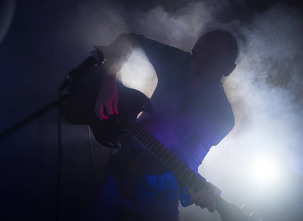 istock Silhouette of guitarist singing into microphone during live performance with backlight 2238972825