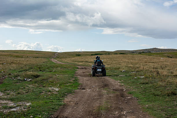 Sporty boyfriend and girlfriend on a mountain riding around on a quad bike
