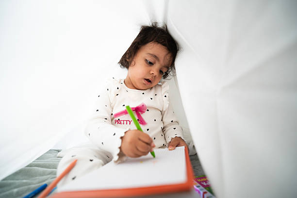 Young child drawing with a crayon while playing indoors at home
