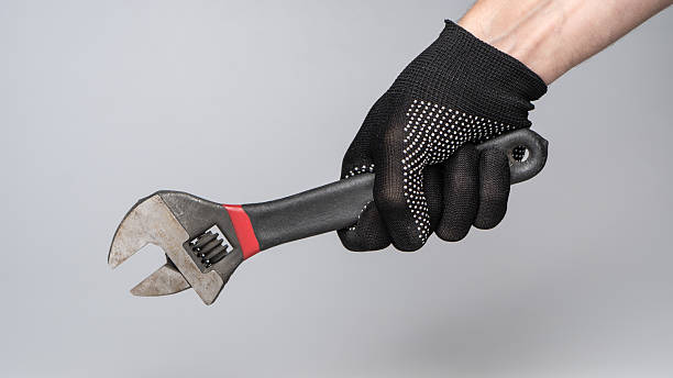 istock Hand in work glove holding adjustable wrench on gray background 2238977251