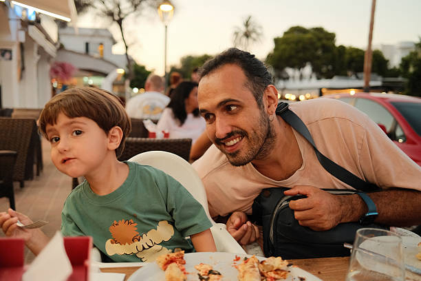 Father and son enjoying dinner at outdoor restaurant
