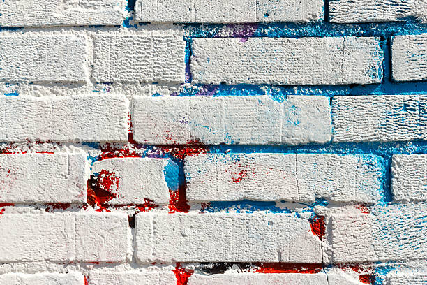Grey and orange paint used to cover up graffiti on an old yellow wall