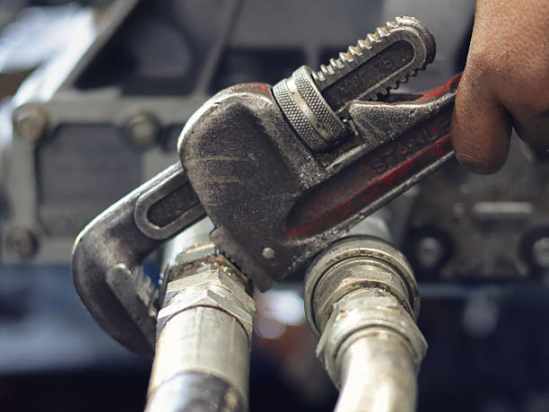 istock mechanic's hand tightening a hose fitting using a pipe wrench. 2238981287