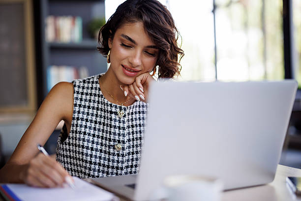 istock Young businesswoman working with laptop and writing notes at modern cafe 2238982152