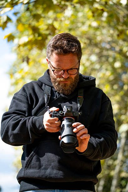 istock Man with beard and glasses checking camera settings in soft natural light 2238982925
