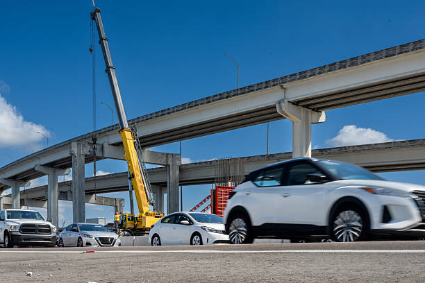 istock vehicles passing by, with large crane in the background working on expressway expansion construction site 2238983914