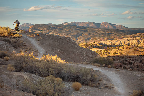 Solo man mountain biking on extreme desert badlands landscape terrain as the sunset light skips across the scenery in golden hues.  Such beautiful nature scenery and outdoor sports and wellness can found while riding the White Ridge trails of central New Mexico, USA.