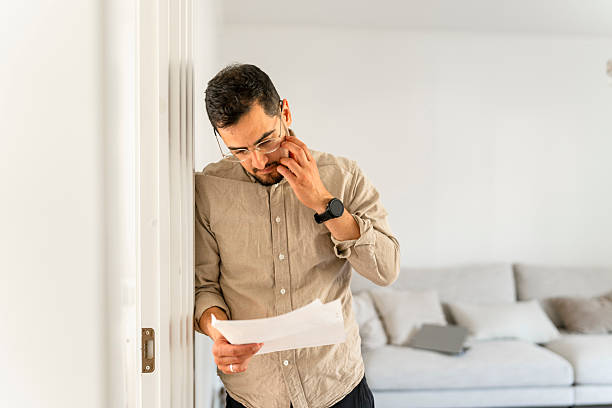 istock Focused man reviews financial documents at home while on a call for work 2238985998