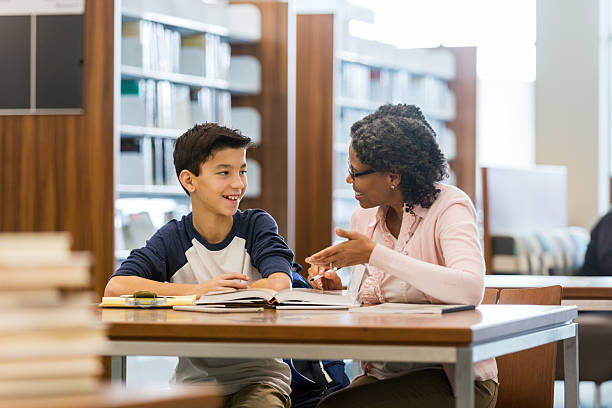 istock Student and teacher collaborate in library, discussing lessons with focus and smiles. 2238997699