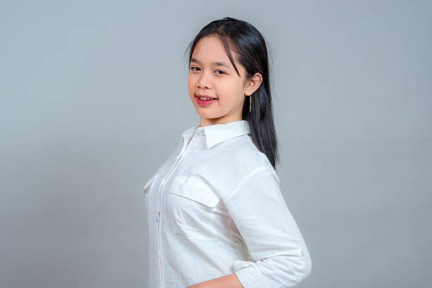 istock Confident young Asian woman smiling subtly with a relaxed pose, head slightly tilted, and hands on hips. Friendly, approachable expression in studio setting. 2238998643