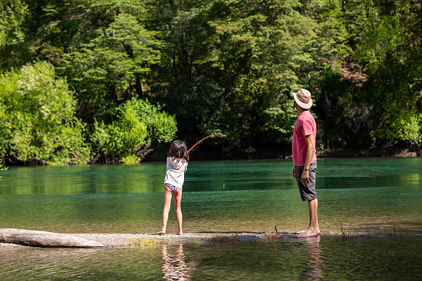 Father teaching his young daughter to fish backwards on the Manso River in Patagonia, Argentina.