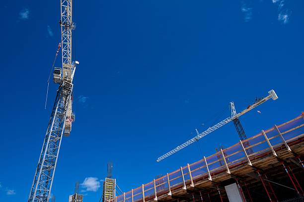 istock looking up at two construction cranes in construction site against blue sky 2238999598