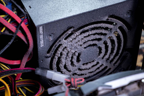 Dust covers the fan and wires of a computer power supply unit, revealing the need for cleaning during routine hardware maintenance and inspection of electronic components.