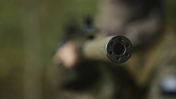 istock Camouflaged soldier with AR15 carbine. Rifle with a collimator aiming at the camera. Selective focus. Military war recon 2239000949