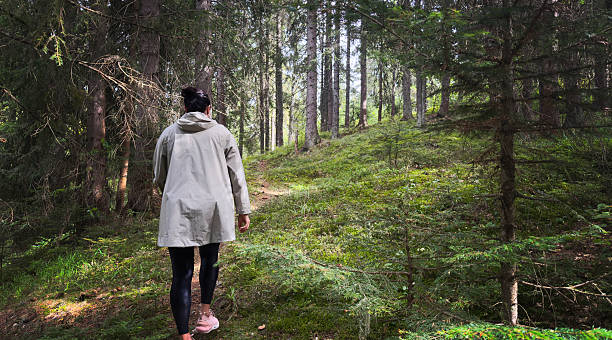 istock Woman Walking Through Forest Path In Light Beige Coat 2239001026