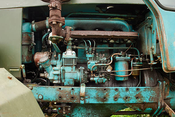 Closeup showing old blue tractor engine with visible rust and mechanical components, highlighting detailed structure of machinery and worn metal surfaces in outdoor setting