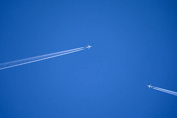 istock two white jets flying towards each other with long contrails in front of a blue sky 2239002600